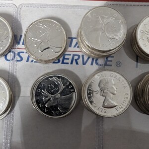 May include: A collection of Canadian 25-cent coins featuring a caribou on one side and Queen Elizabeth II on the other. The coins are dated 1962 and 1963.
