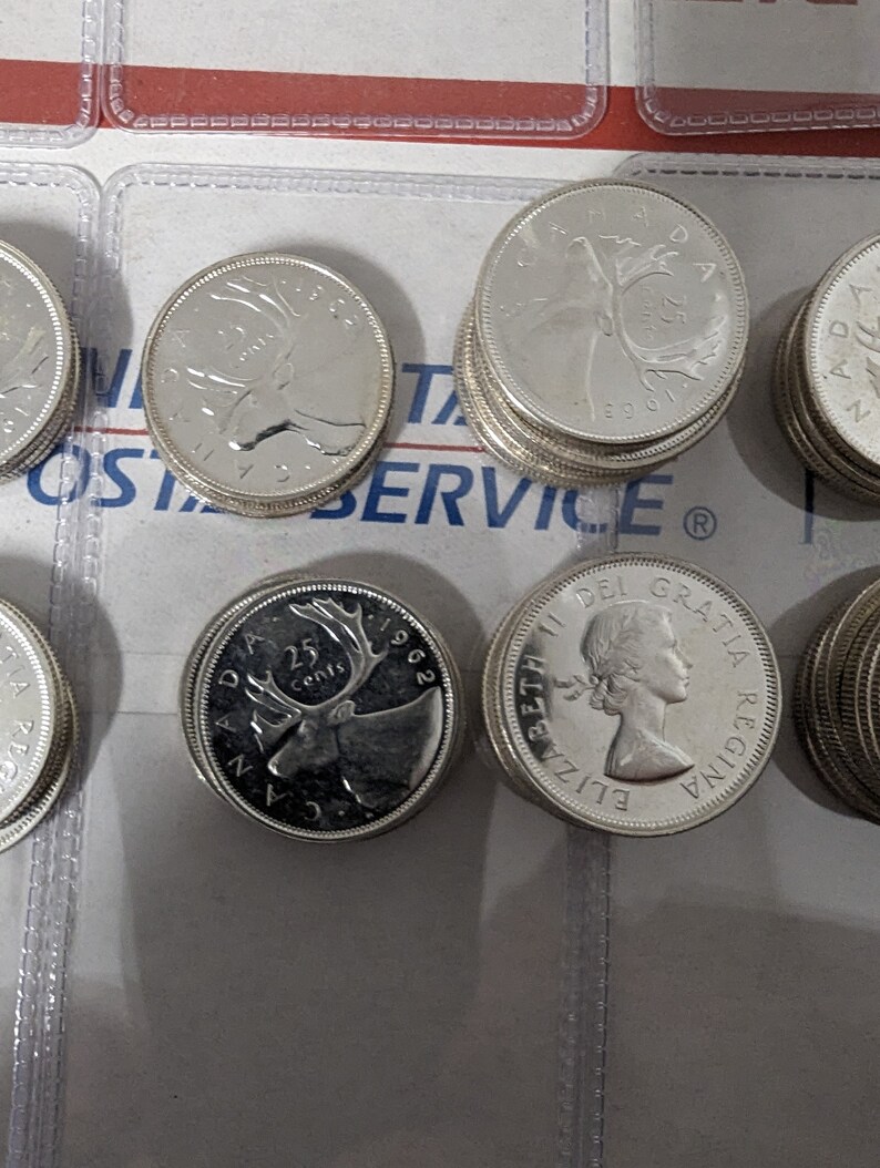 May include: A collection of Canadian 25-cent coins featuring a caribou on one side and Queen Elizabeth II on the other. The coins are dated 1962 and 1963.