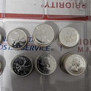 May include: A stack of Canadian 25-cent coins featuring a caribou on one side and a portrait of Queen Elizabeth II on the other. The coins are silver in color and have a smooth, shiny finish.