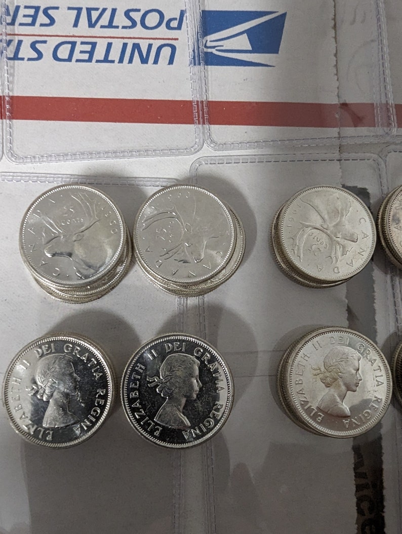 May include: A collection of silver Canadian coins featuring the profile of Queen Elizabeth II and a moose. The coins are arranged in two rows on a white surface.