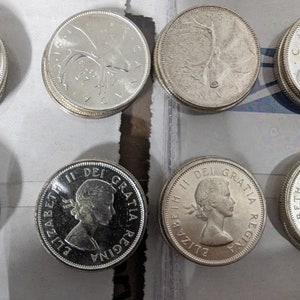 May include: Close-up of six silver Canadian coins. The coins feature a profile of Queen Elizabeth II and a caribou on the obverse and reverse sides. The coins are in good condition and have a shiny finish.
