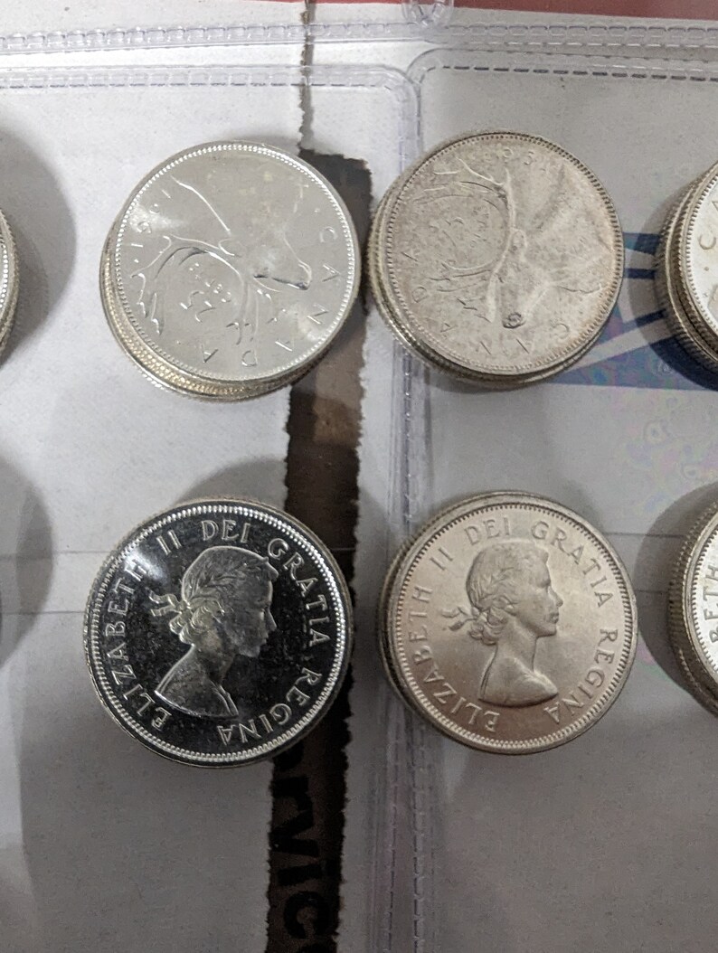 May include: Close-up of six silver Canadian coins. The coins feature a profile of Queen Elizabeth II and a caribou on the obverse and reverse sides. The coins are in good condition and have a shiny finish.