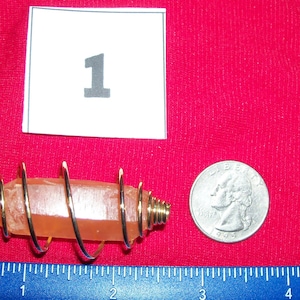 May include: A gold-wrapped orange crystal pendant with a black cord. The pendant is about 1 inch long and is next to a US quarter for size comparison.