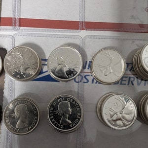 May include: A collection of silver Canadian coins featuring the profile of Queen Elizabeth II and a caribou on the reverse side.