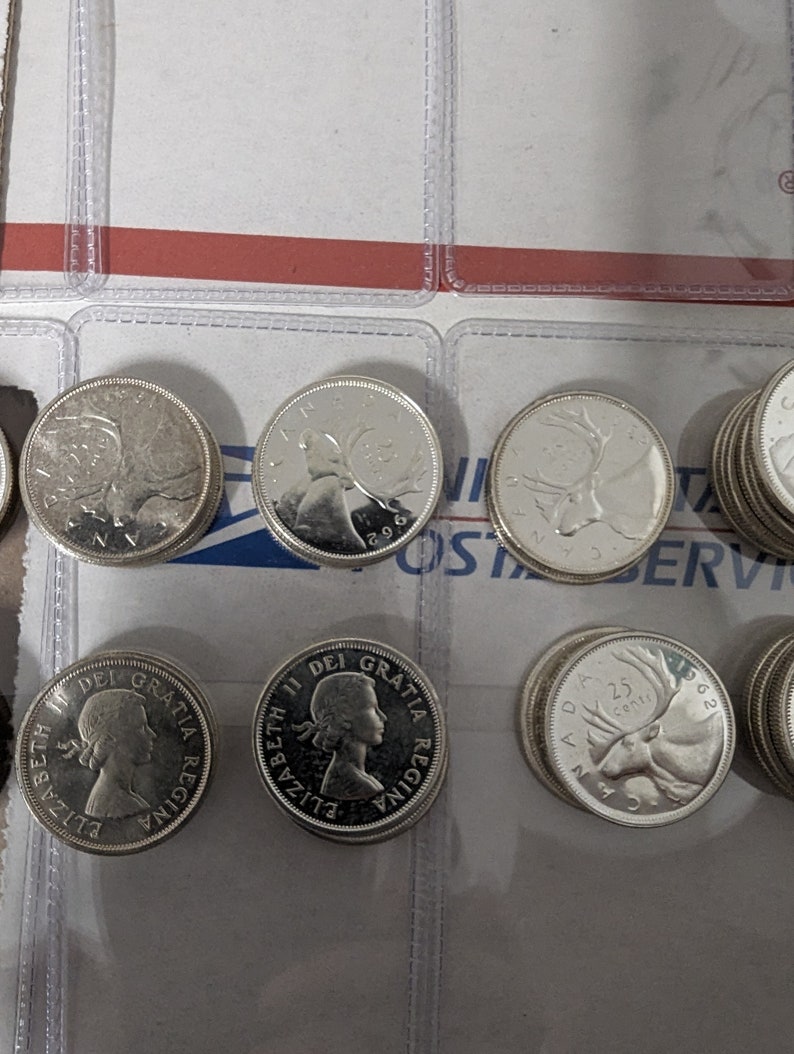 May include: A collection of silver Canadian coins featuring the profile of Queen Elizabeth II and a caribou on the reverse side.