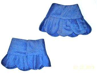 Può includere: Un paio di polsini in tessuto blu intenso con bordo smerlato. Ogni polsino presenta una fascia superiore liscia a tinta unita e una sezione inferiore composta da segmenti arrotondati e sovrapposti a forma di petalo.