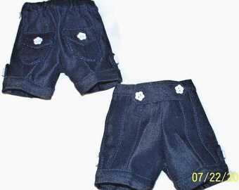 Può includere: Due paia di pantaloncini in denim blu scuro. Un paio presenta tasche posteriori con bottoni bianchi a forma di fiore. L'altro paio ha una cintura anteriore con due bottoni bianchi a forma di fiore e cuciture verticali. Il testo 07/22/20 è visibile.