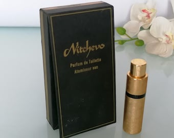 May include: A black box with gold lettering that reads "Nichevo Parfum de Toilette Atomiseur sac" and a gold and black atomizer perfume bottle.