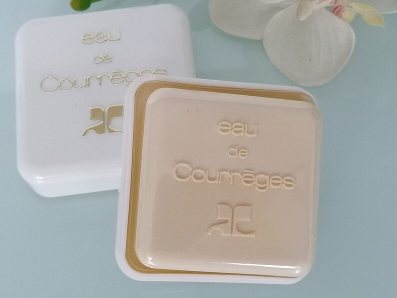 Puede incluir: Dos cajas cuadradas blancas con letras doradas. La caja superior dice "eau de Courr&egrave;ges" y la caja inferior dice "eau de Courr&egrave;ges". Ambas cajas tienen un logotipo "C" dorado.