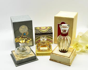 Puede incluir: Una variedad de frascos de perfume vintage, cada uno en su embalaje original. Los frascos varían en forma y diseño, con detalles dorados y elementos decorativos. El embalaje incluye cajas con diseños florales y ornamentados.