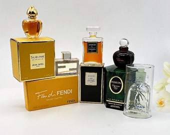 May include: A collection of miniature perfume bottles in various colors and designs. The bottles are arranged on a white surface. The bottles include: Sublime Jean Patou, Fan di Fendi, Coco Chanel, Coco Chanel, Poison Christian Dior, and Fleur de Rocaille.