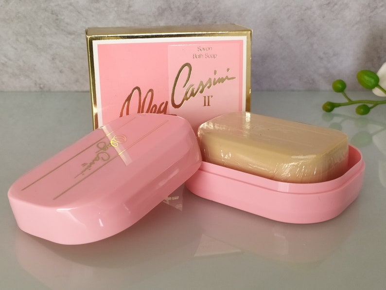 May include: A pink soap dish with a bar of soap inside. The soap dish has a gold trim and the text "Mia Cassini II" is printed on the box.