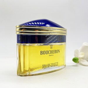May include: A blue and gold bottle of Boucheron Paris Eau de Toilette Pour Homme cologne. The bottle has a textured glass design and a gold cap.