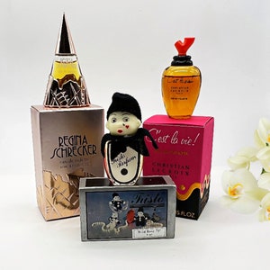 Pode incluir: Uma coleção de frascos de perfume vintage, incluindo um frasco pequeno de eau de toilette Regina Schrecker, um frasco pequeno de eau de toilette Christian Lacroix 'C'est la vie!' e um frasco pequeno de perfume 'Tristo'. Os frascos estão dispostos sobre uma superfície branca.
