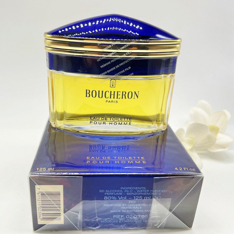 May include: A blue and gold bottle of Boucheron Paris Eau de Toilette Pour Homme cologne. The bottle is 125 ml or 4.2 fl oz. The bottle is sitting on a blue and white box with the ingredients listed on the side.
