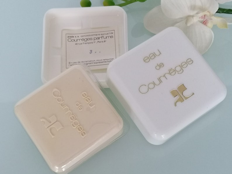 Puede incluir: Dos cajas cuadradas blancas con letras doradas. La caja superior dice "eau de Courr&egrave;ges" y la caja inferior dice "eau de Courr&egrave;ges".