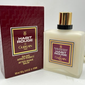 Può includere: Una scatola rossa e dorata con il testo "Habit Rouge De Guerlain Paris" e una bottiglia di balsamo dopobarba con lo stesso testo. La bottiglia è trasparente e ha un'etichetta bianca con il testo "Baume Apres Rasage After Shave Balm Habit Rouge De Guerlain Paris".