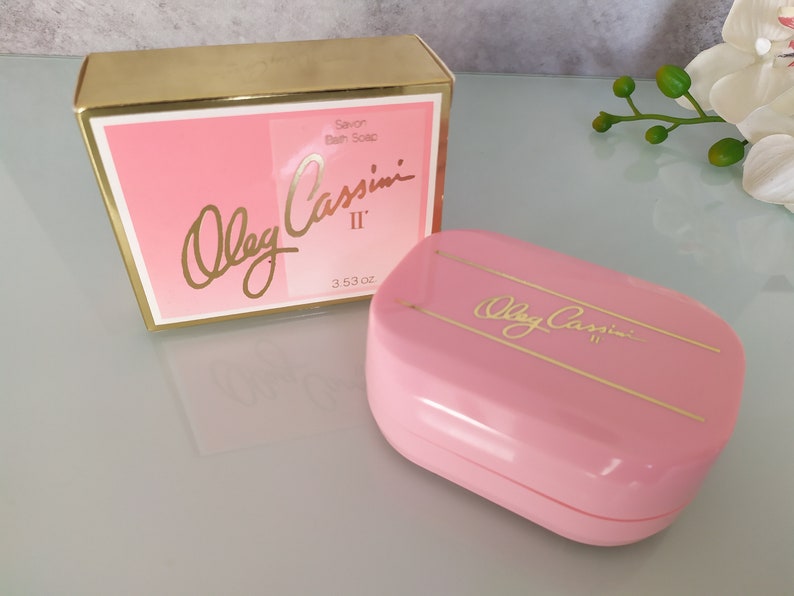 May include: A pink and gold bar soap in a box. The soap is labelled "Oleg Cassini II" and the box says "Savon Bath Soap".