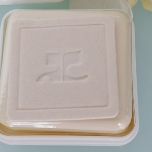 Puede incluir: Un recipiente cuadrado blanco con una tapa de pl&aacute;stico transparente. El recipiente tiene un logotipo en relieve que dice "RC".