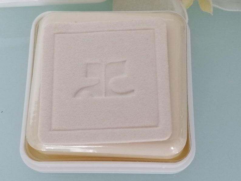 Puede incluir: Un recipiente cuadrado blanco con una tapa de pl&aacute;stico transparente. El recipiente tiene un logotipo en relieve que dice "RC".