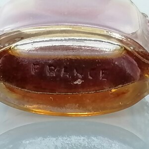 May include: A clear glass bottle with a gold rim and a brown liquid inside. The bottom of the bottle has the word "FRANCE" embossed on it.