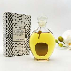 May include: A clear glass bottle of perfume with a gold cap and a brown label. The bottle is sitting on a white surface. The box is white with black geometric patterns and text that reads "Ce produit ne peut &ecirc;tre vendu que par les d&eacute;positaires agr&eacute;&eacute;s par la soci&eacute;t&eacute; GUERLAIN conform&eacute;ment &agrave; ses conditions g&eacute;n&eacute;rales de ventes, Copyright GUERLAIN 1967 EMB 92026A 86% WYE 3IB 4".