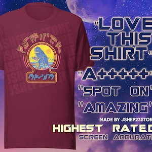 May include: A maroon t-shirt with a retro-style graphic of a dinosaur holding a drink. The graphic is surrounded by a neon pink and blue border. The text "LOVE THIS SHIRT" is in a blue box on the right side of the image. The text "A+++++" is in a blue box below the first text. The text "SPOT ON" is in a blue box below the second text. The text "AMAZING" is in a blue box below the third text. The text "MADE BY JSHEP23STORE" is in a white box below the fourth text. The text "HIGHEST RATED SCREEN ACCURATE" is in a white box below the fifth text.