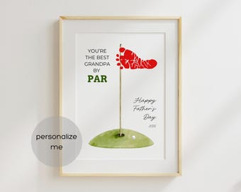 May include: Framed print with a golf theme. The artwork features a red footprint flag on a green golf course. Text includes "You're the Best Grandpa by Par" and "Happy Father's Day 2026". The print is in a light wood frame.
