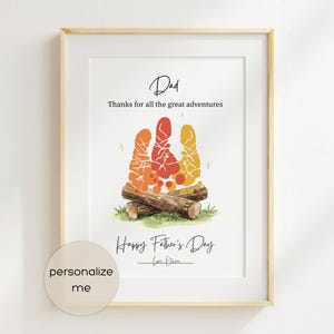 Op de afbeelding: Ingelijste kunstdruk met een licht houten frame. De print toont een kampvuurontwerp gemaakt van kleurrijke handafdrukken, met de woorden "Papa" en "Fijne Vaderdag". De tekst "Bedankt voor alle geweldige avonturen" is ook opgenomen.