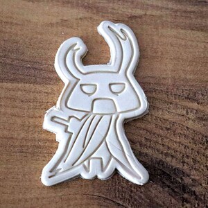 May include: A white ceramic mug with a black handle and the text "But First, Coffee" in a bold, black font. The mug is set against a blurred background, suggesting a cozy setting. The mug appears to be approximately 4 inches tall.