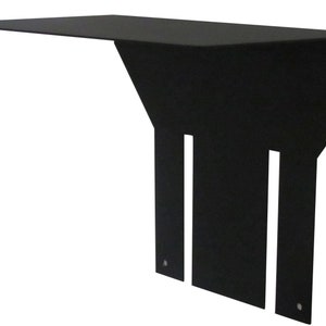 May include: A black metal shelf with a horizontal top and a vertical support structure. The support has three rectangular cutouts and two small holes. The shelf is designed to be mounted on a wall.