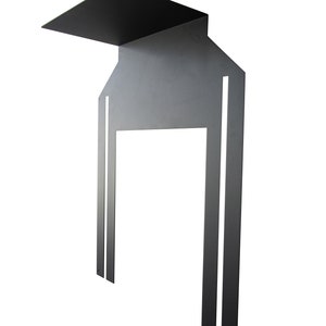 May include: A modern, minimalist black metal sculpture with a geometric design. The sculpture features a rectangular top, a house-shaped body with a large opening, and two vertical bars extending downwards. The piece is designed to be mounted on a wall.