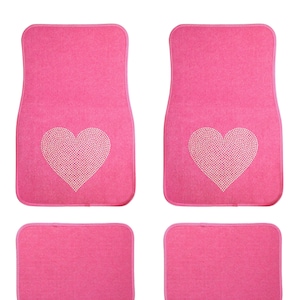May include: Set of four pink car floor mats with a rhinestone heart design. Two mats feature a large heart design, while the other two mats are plain.