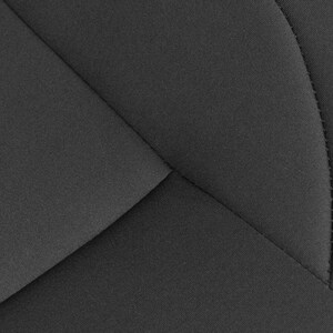 May include: Close-up of a black fabric with a geometric pattern of stitched seams. The fabric has a textured surface.
