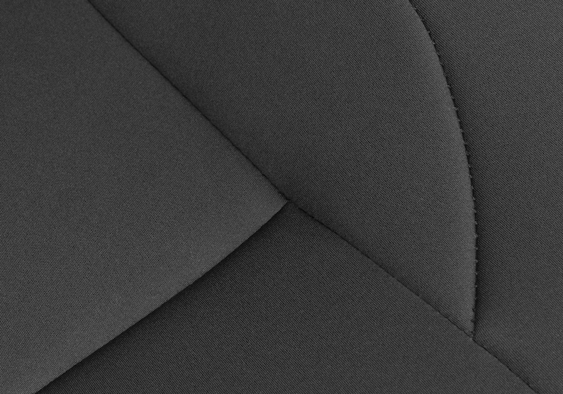 May include: Close-up of a black fabric with a geometric pattern of stitched seams. The fabric has a textured surface.