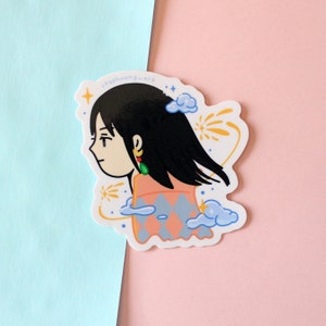 Może przedstawiać: Wycięta naklejka z kresk&oacute;wkową ilustracją osoby z czarnymi włosami, ubranej w brzoskwiniowo-niebieską bluzkę we wzory i zielone kolczyki. Naklejka ma białą obw&oacute;dkę i zawiera tekst "stephuang-art".