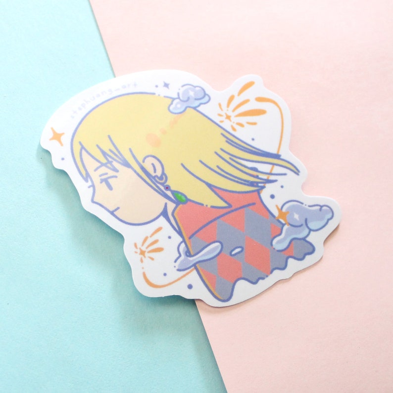 Może przedstawiać: Wycięta naklejka z ilustracją w stylu anime postaci z blond włosami, ubranej w czerwono-szary str&oacute;j w wzory. Naklejka ma białą obw&oacute;dkę i zawiera tekst "stephjang-art". Tło jest jasnoniebieskie i r&oacute;żowe.