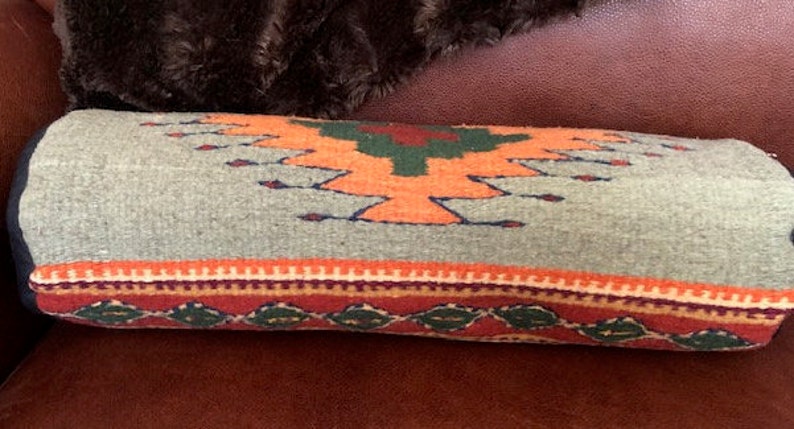 May include: A gray and orange patterned throw pillow with a geometric design. The pillow is made of woven fabric and has a fringe border.