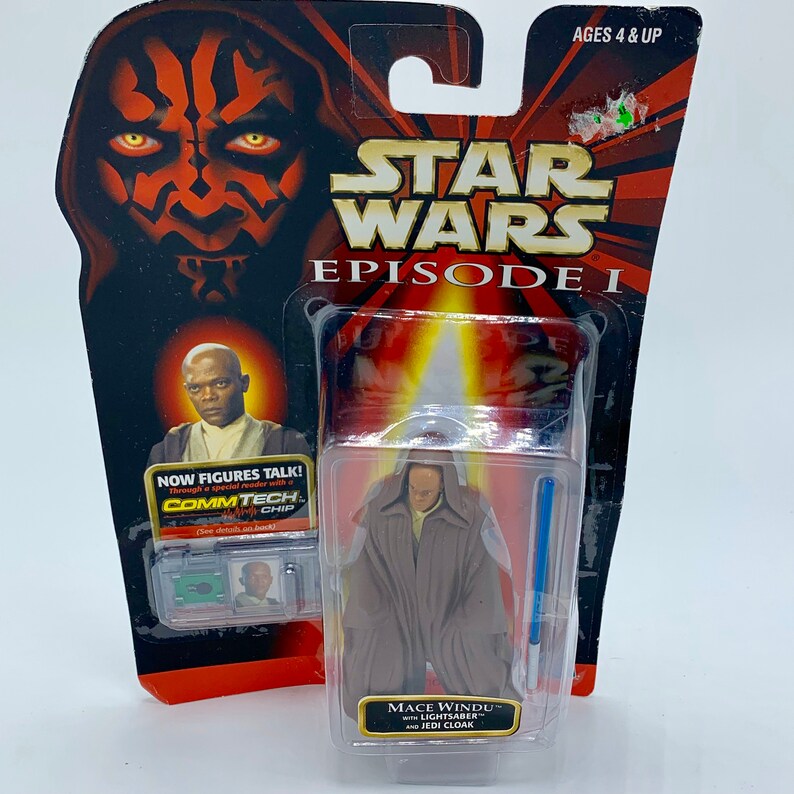 May include: A Star Wars Episode I action figure of Mace Windu with a lightsaber and Jedi cloak. The figure is packaged in a plastic blister pack with a red and black background featuring Darth Maul's face. The packaging also includes a CommTech chip.