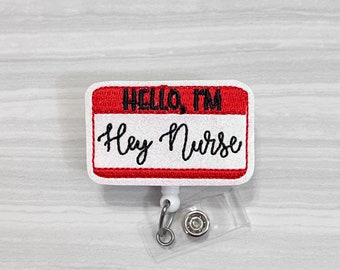 May include: White plastic badge holder with a red and white name tag that says "Hello, I'm Hey Nurse".