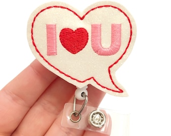 May include: White glitter heart-shaped badge holder with a red heart and the words "I love you" in pink lettering.