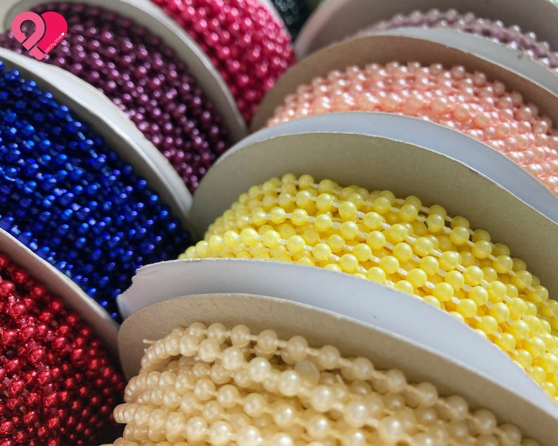 K&ouml;nnte beinhalten: Spulen mit farbigem Perlenbesatz in verschiedenen Farben, darunter Rot, Rosa, Gelb, Wei&szlig;, Blau und Lila.