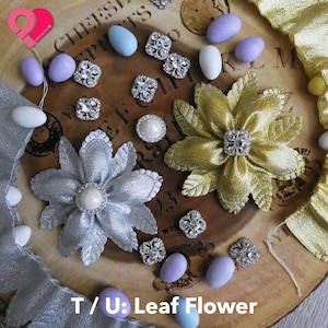 May include: A set of two fabric flowers in metallic silver and gold, accompanied by several small silver-toned rhinestone embellishments and smooth, oval-shaped pastel-colored beads in shades of light blue, white, and lavender.