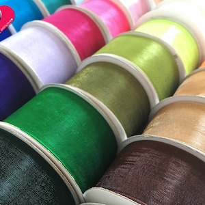 May include: A variety of colorful ribbon spools in different shades of green, brown, beige, blue, and pink. The ribbon is made of a sheer, silky material.
