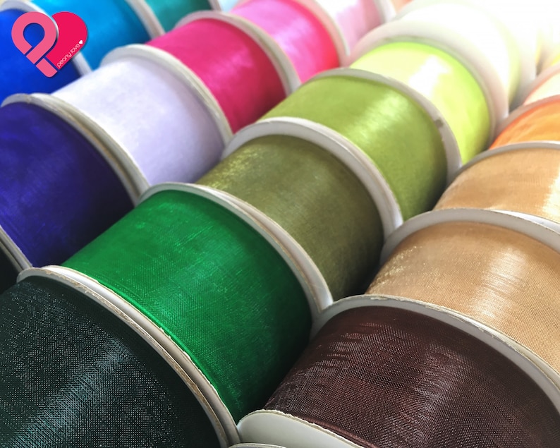 May include: A variety of colorful ribbon spools in different shades of green, brown, beige, blue, and pink. The ribbon is made of a sheer, silky material.