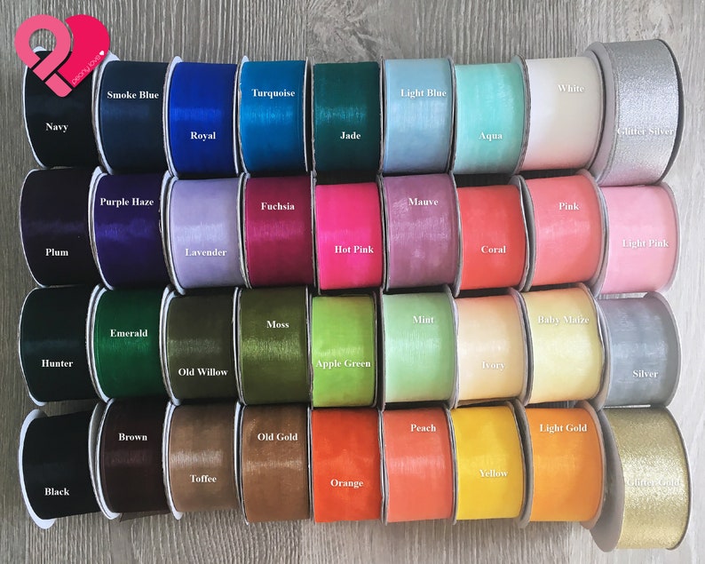 May include: A collection of 40 spools of ribbon in various colors, including black, white, red, green, blue, and yellow. The ribbon is arranged in rows of four, with each spool labeled with its color name.