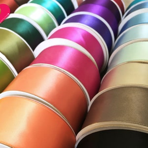 May include: A collection of colorful satin ribbon spools. The ribbons are in various shades, including orange, pink, green, and blue. The spools are neatly stacked, showcasing the glossy texture of the ribbon.