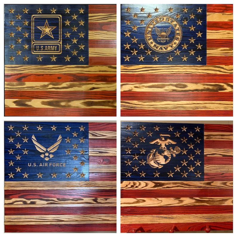 May include: Four wooden American flags, each with a different branch of the military emblem. The flags are all distressed and have a rustic look. The emblems are "U.S. Army", "U.S. Navy", "U.S. Air Force", and "U.S. Marine Corps".