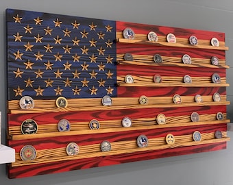 May include: A wooden American flag with a red, white and blue design. The flag has shelves for displaying challenge coins. The shelves are filled with various challenge coins.