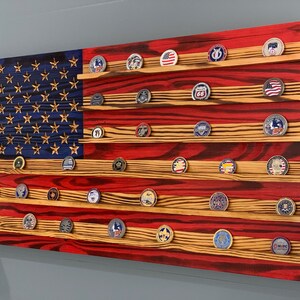 May include: A wooden American flag with red, white, and blue stripes. The flag has a blue field with white stars and is designed to hold challenge coins. The flag is made of reclaimed wood and has a distressed finish.